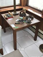 Full view of wooden side table with items on top showing construction and condition.