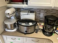 Photo showing all main kitchen appliances on the counter: KitchenAid stand mixer, Regal bread maker, Crock-Pot slow cooker, Sunbeam coffee maker, and baking accessories.