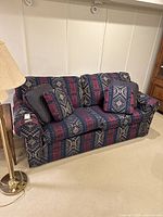 Front view of the sofa bed showing the patterned upholstery and gathered cushions with matching accent cushions.