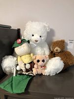 Group shot of four stuffed toys showing white bear, brown bear, Ty Beanie Baby pig, and golf character doll with golf bag