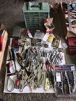 Full overview of all tools laid out on floor including wrenches, pliers, hammers, multimeter, small hand saw, and tool organizer cabinet