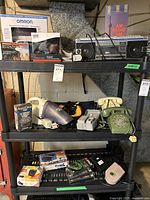 Three-shelf black metal unit holding various vintage phones, electronics, and accessories showing all main items in the lot.