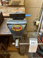 Front view of the R.E. Dixon metal vise mounted on a wooden workbench, showing handle, jaws and label.