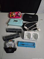 Photo showing multiple Nintendo 3DS, DS, and Wii accessory items including cases, cartridge holders, charging dock, and a Guitar Hero guitar controller accessory.