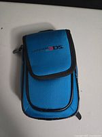 Front view of blue Nintendo 3DS carrying case with flap pocket and logo