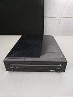 Front view of black Nintendo Wii console showing power and reset buttons, disc slot, eject button, and Wii branding.