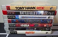 Stacked view of 7 PlayStation 3 game cases showing titles and condition.