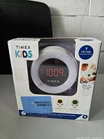 Front view of Timex Kids Sleep Training Clock in original packaging showing digital time display and branding.