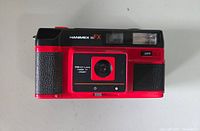 Front view of red and black Hanimex 35 FX camera showing lens and on/off switch.