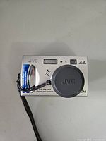 Front view of silver JVC GC-QX3HD camera showing lens cap, flash, and 3.3 megapixel label.