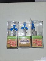 Three Zelda sword wine bottle stoppers, each in clear plastic packaging showing blue sword tops and cork bases. Two have The Master Cork branding, one shows Arcade Block Exclusive label.