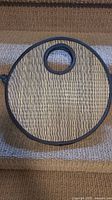 Front view of circular handbag with bamboo weave and black fabric border, showing circular cut-out handle