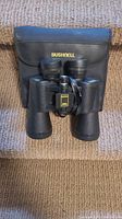 Front view of Bushnell Insta Focus binoculars showing lens and carrying case with Bushnell logo.