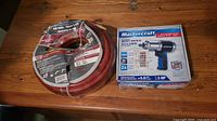 Photo shows Mastercraft brand air hose and the boxed impact wrench on a wooden surface.