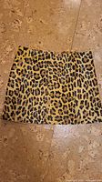 Top-down photo of a ladies mini skirt showing leopard print fur material on a floor surface.