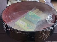 Red and black lacquer mixing bowl covered with plastic wrap with bamboo rolling mat pack inside.