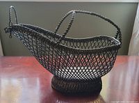 Side view of vintage metal wine cradle basket showing wire mesh structure and braided wire handles.