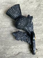 Angled view of black cast iron Scottish thistle decorative piece showing texture and thickness