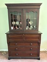Front view of the antique secretary desk with hutch showing original wavy glass doors and wooden drawers below.