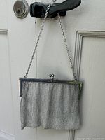 Full view of silver mesh evening bag with chain strap hanging on door knob