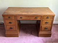 Front view of antique solid walnut desk showing six drawers and worn bookmatched veneer top