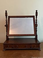 Front view of the antique walnut vanity mirror with tilting rectangular mirror and three small drawers below.