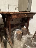 Side view of antique solid wood workbench showing drawer and A-frame leg design