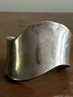 Front view showing the wavy design and polished silver surface of the cuff bracelet.