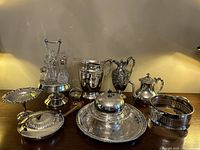 Overall view of the silver plated serving items grouped together on a wooden table surface, showing all included pieces.