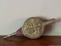 Side view showing embossed brass plate with a couple in period clothing and a fence background.