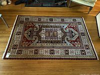 Full view of the rectangular vintage Kazak rug showing entire geometric design and multicolor palette on hardwood floor.