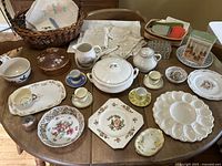 Full view of vintage porcelain china set and embroidered linens arranged on a wooden table.