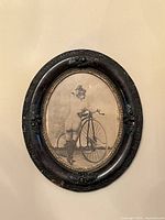 Frontal photo of the oval framed black and white print showing the entire artwork and frame.