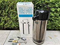 Bunn Air Pot stainless steel thermal beverage server next to original box and four novelty cheese spreaders laid at base