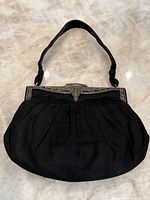 Front full view of black evening purse with marcasite embellished clasp and strap visible.