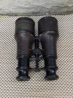 Front angled view of antique binoculars showing leather texture, metal patina, and eyepieces.