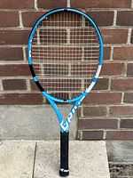 Full view of racket against brick wall showing frame and handle