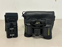 Two Bushnell binoculars paired with respective carrying cases displayed together on table.