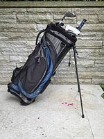 Full view of Callaway stand golf bag showing black, gray, and blue colors, bag standing with legs extended, showing clubs inside.
