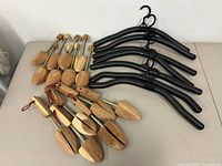 Top-down view of two types of cedar shoe trees arranged alongside black foam hangers on a white table.