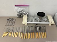 Full lot overview with cutlery sets, bag of flatware, glass teapot on hot tray