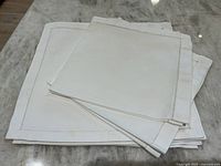 Set of folded white linen napkins on a marble surface, showing the entire lot of napkins stacked.