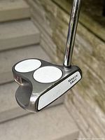 Front and top view of the Odyssey White Hot 2 Ball putter showing the two white circular inserts on the putter head and 'White Hot' branding on the side.