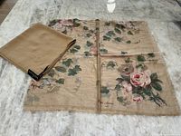 Two scarves laid out, one beige floral print with pink roses and Ralph Lauren signature, other camel silk with RL initials folded neatly.