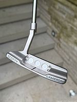 Rear view of putter head showing SCOTTY CAMERON engraving and three circular rear weights