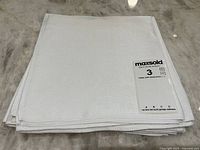 Stack of six white square damask dinner napkins with a MaxSold tag showing lot number 3.