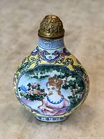 Front view of snuff bottle showing hand painted portrait of young woman in pink dress, surrounded by floral and geometric designs.