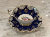Photo showing the teacup seated in the saucer displaying the cobalt blue and gold pattern and the floral medallion inside the cup and on the saucer.