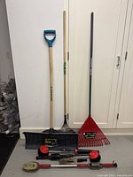 Photo of Yardworks snow pusher, metal leaf rake, red plastic leaf rake, and four car wash brushes