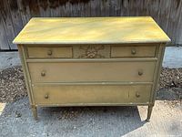 Front view of the antique French provincial three drawer dresser showing faux marble painted top and decorative carving.